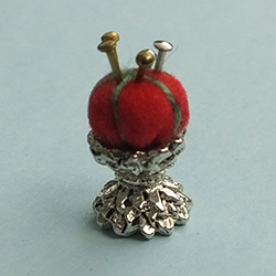 Red pincushion on a silver metal base